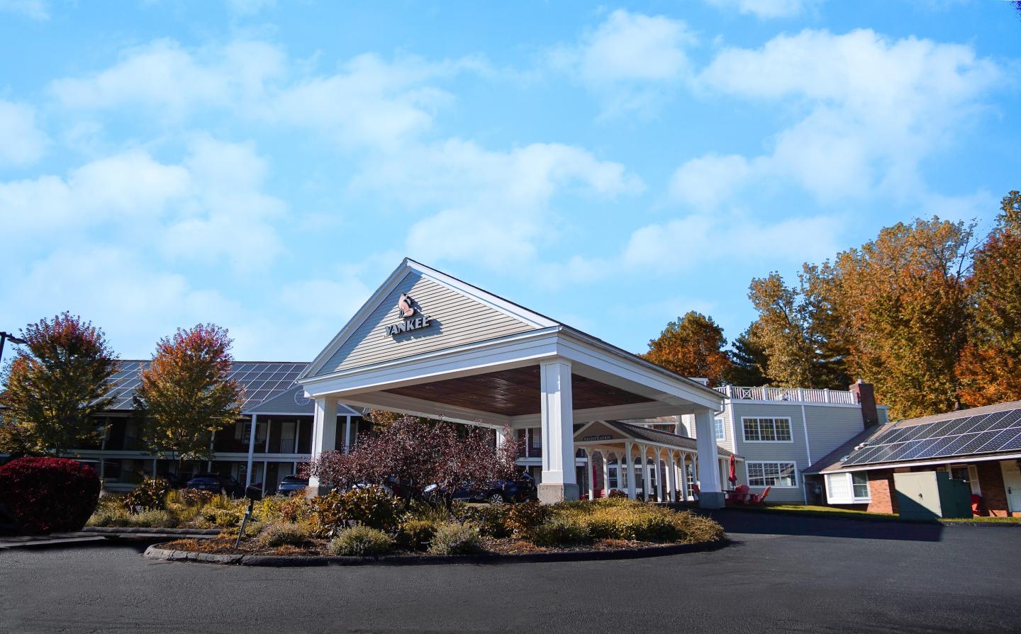 Modern hotel entrance with autumn trees and blue sky.