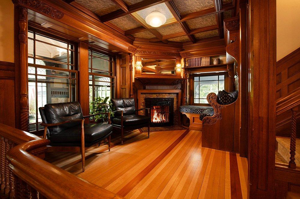 Warm wooden room with fireplace, leather chairs, and large windows.