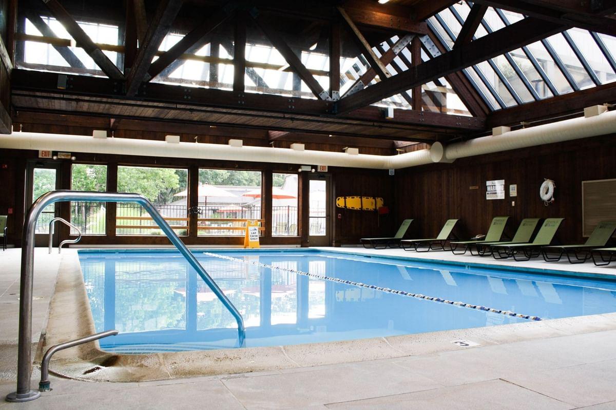 Indoor pool with skylights, surrounded by lounge chairs.