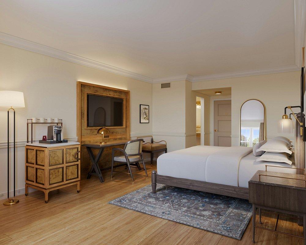 Cozy hotel room with a large bed, desk, and warm lighting.