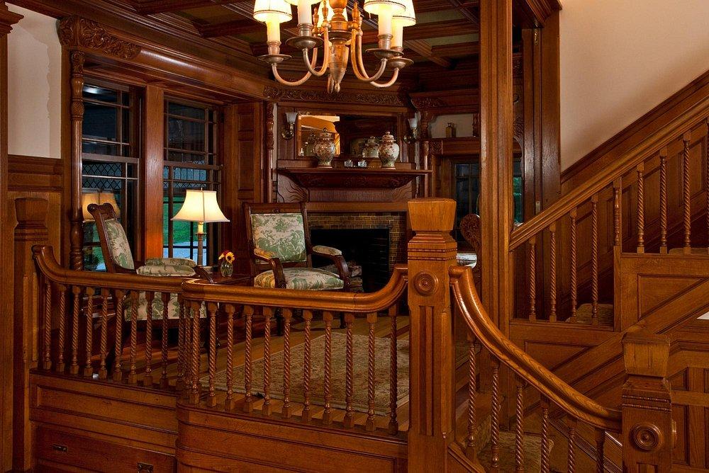 Warm wooden interior, cozy seating by fireplace, elegant chandelier.