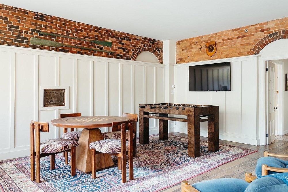 Dining room with table, chairs, TV, and foosball table on a patterned rug.