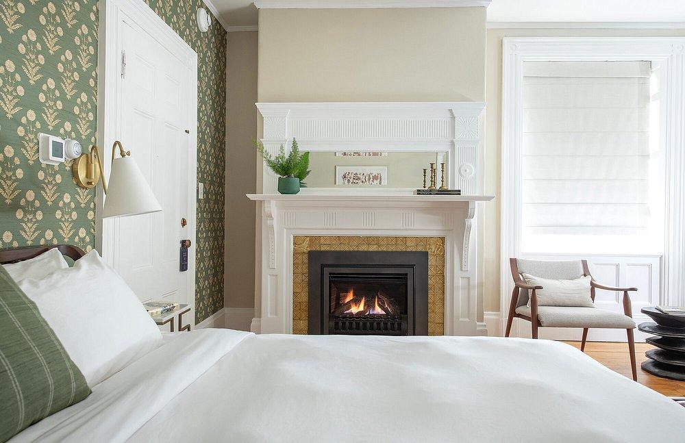 Cozy bedroom with fireplace, green wallpaper, and white bedding.