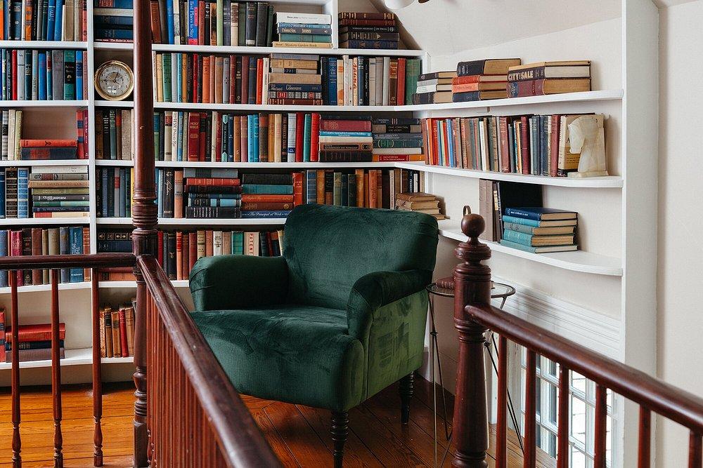 Cozy library nook with a green armchair and shelves of colorful books.
