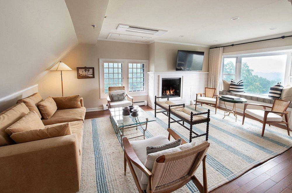 Spacious living room with beige sofas, fireplace, and large windows.