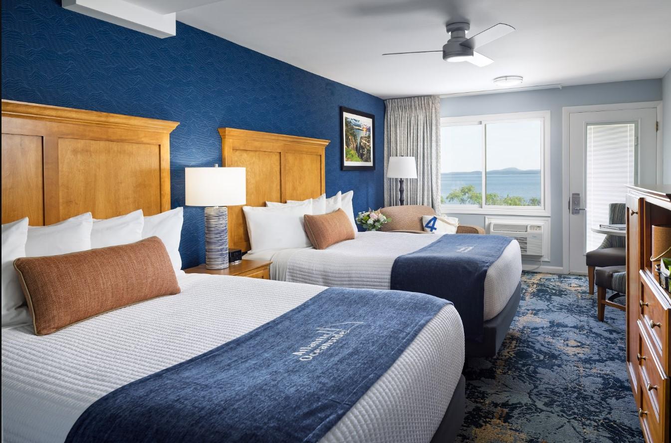 Hotel room with two beds, sea view, and blue decor.
