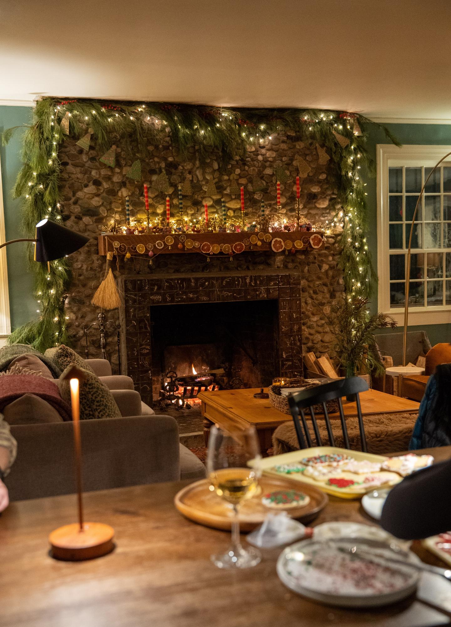 Cozy living room with lit fireplace, decorated with garlands and candles.