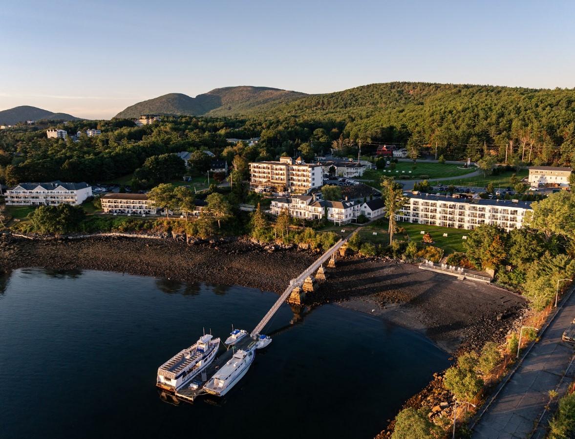 Scenic coastal resort with docked boats, surrounded by green hills.