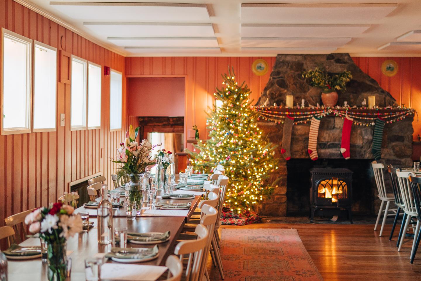 Cozy dining room with Christmas tree and decorated fireplace.