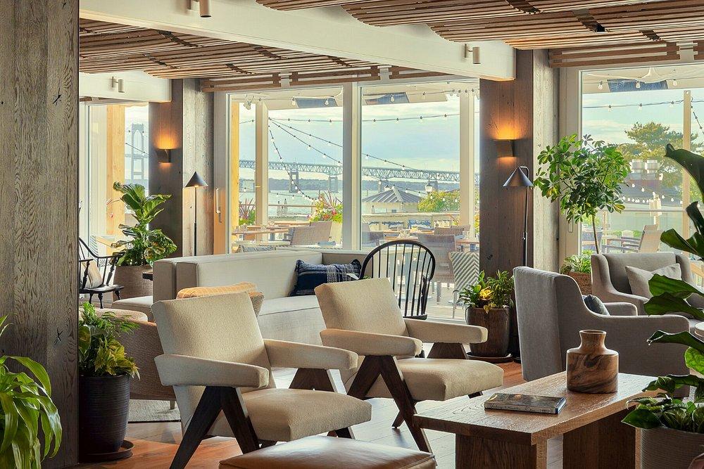 Stylish lounge with chairs and plants, large windows showing a bridge view.