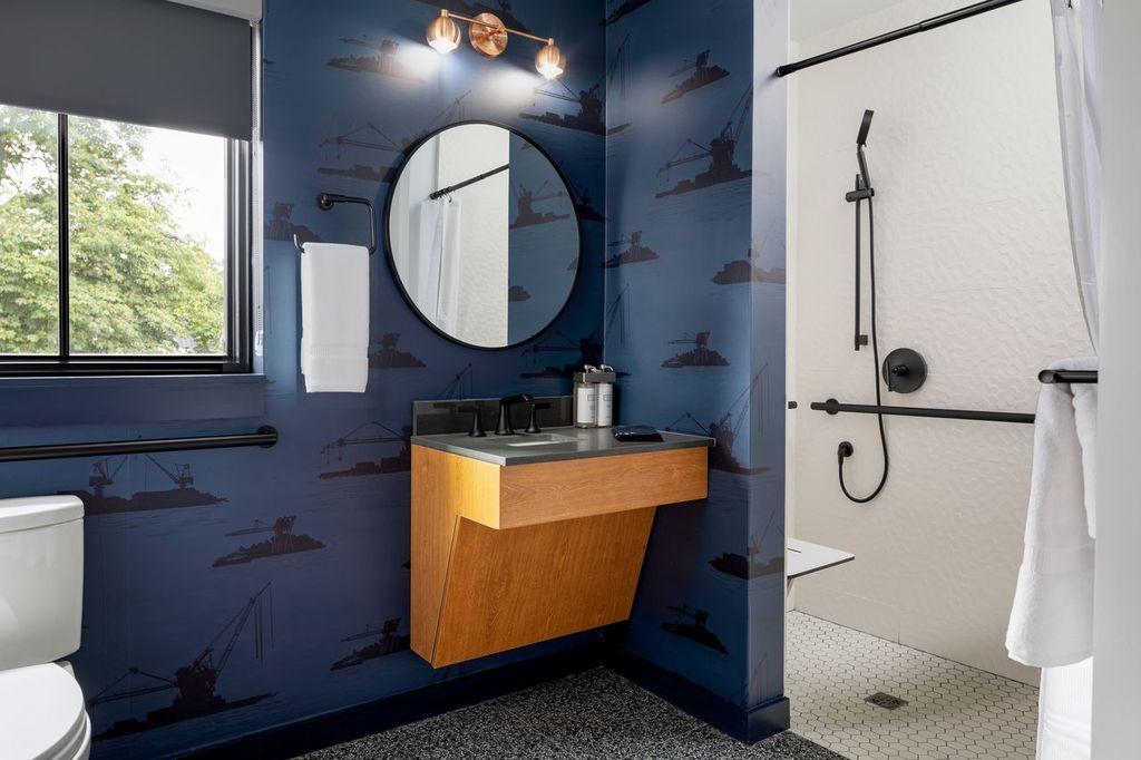 Nautical-themed bathroom with round mirror and walk-in shower.