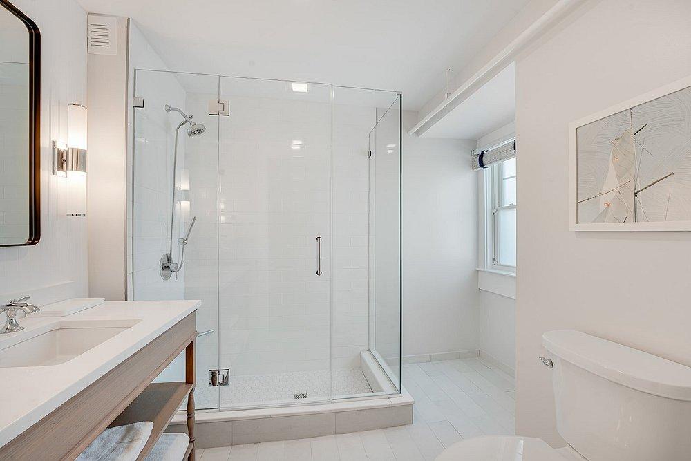 Bright white bathroom with a glass shower, vanity, and toilet.