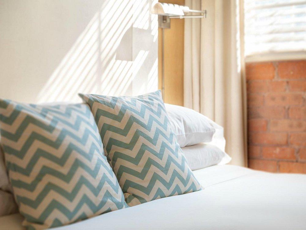 Chevron-patterned pillows on a sunlit bed.
