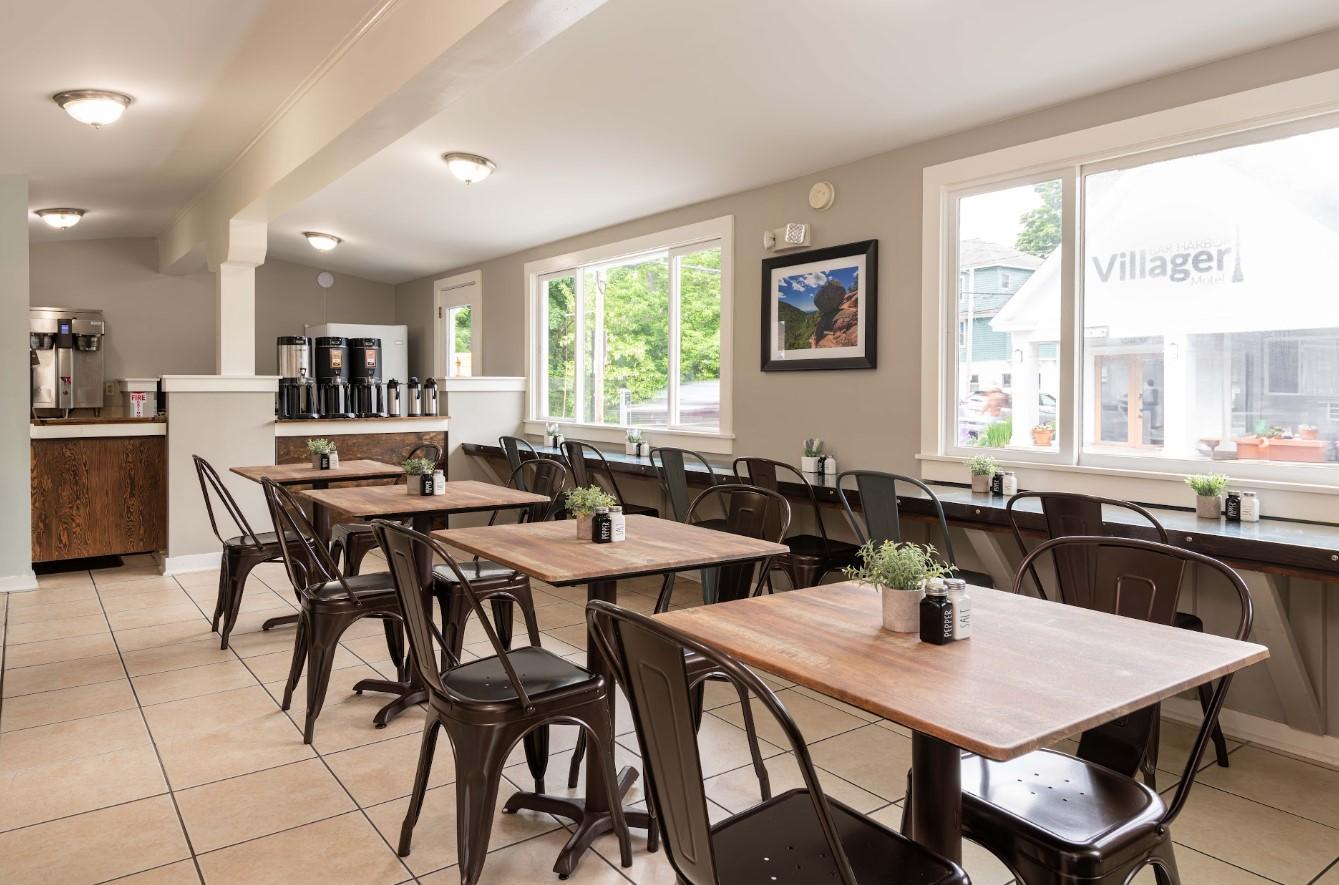 Restaurant interior with wooden tables, metal chairs, and large windows.
