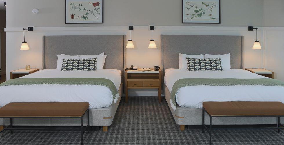 Two neatly made beds in a hotel room with modern decor.