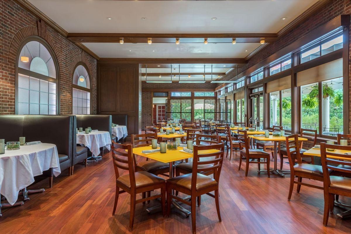 Spacious, sunlit restaurant with wooden floors and table settings.
