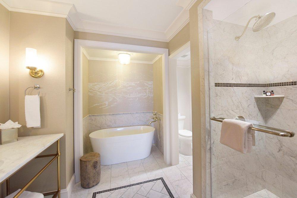 Luxurious bathroom with tub, glass shower, and vanity in neutral tones.