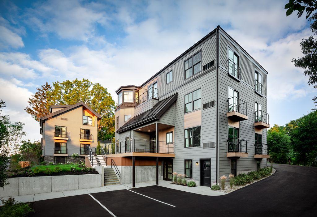Modern apartment building with large windows and a sloped roof.