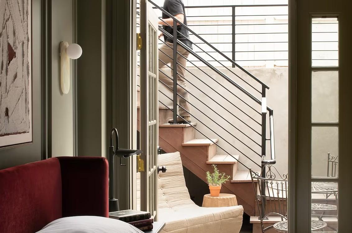 Bedroom with open door to a staircase and potted plant on step.