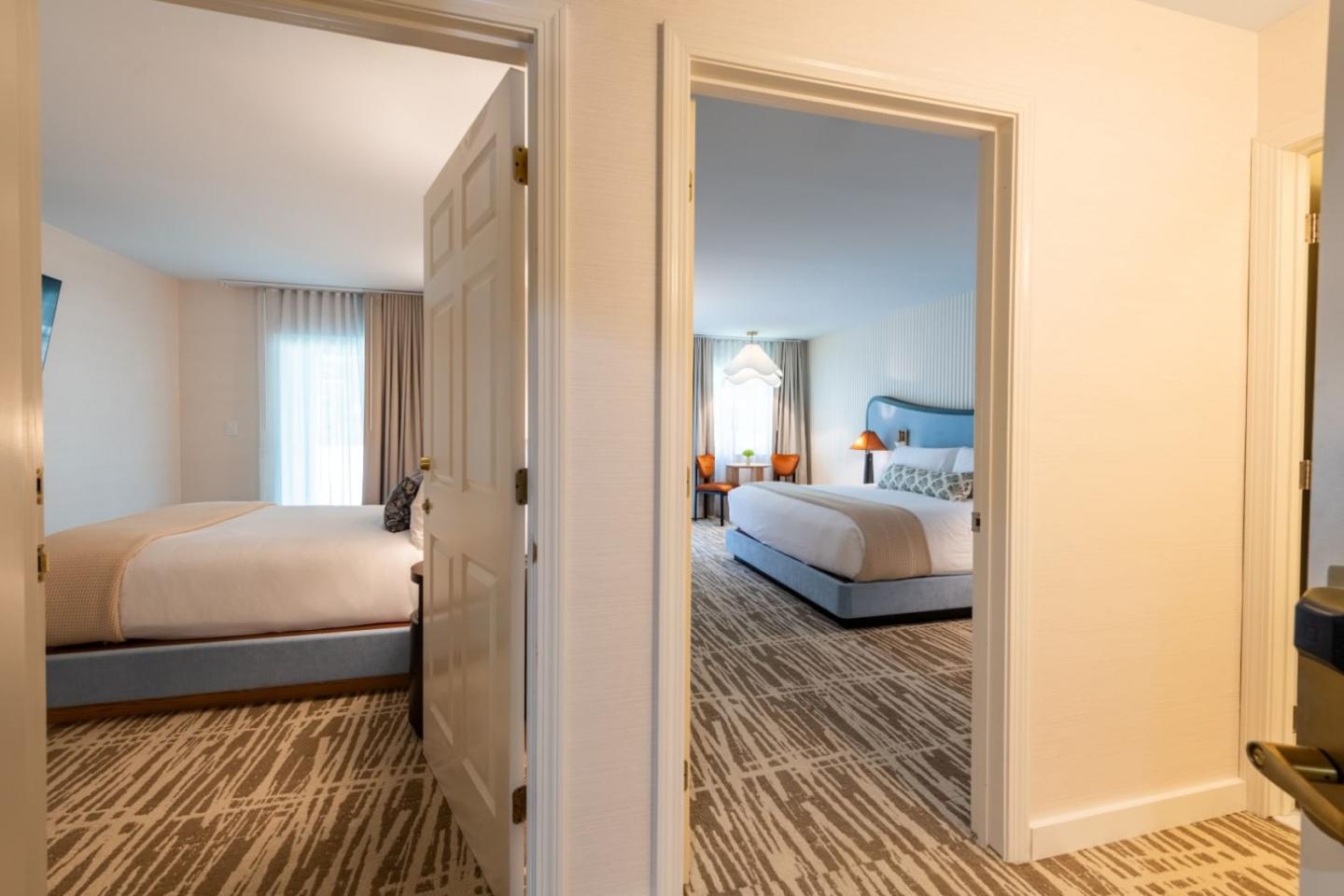 Two adjoining hotel rooms with double beds and beige walls.