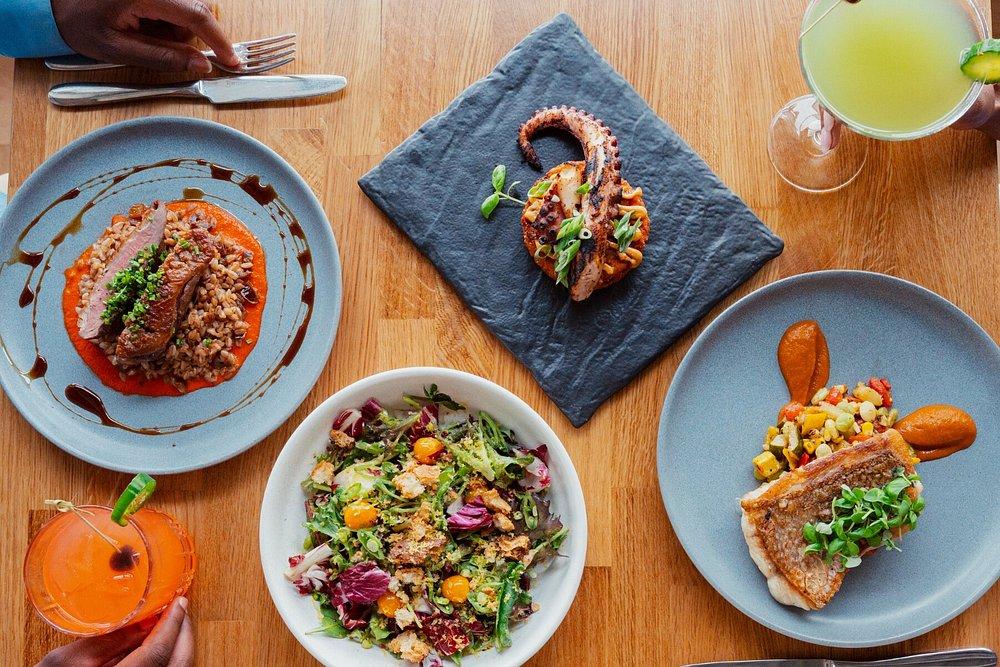 A table with varied dishes and drinks, including seafood and salad.