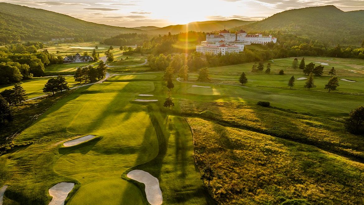 Golf course at sunset with mountains in the background.
