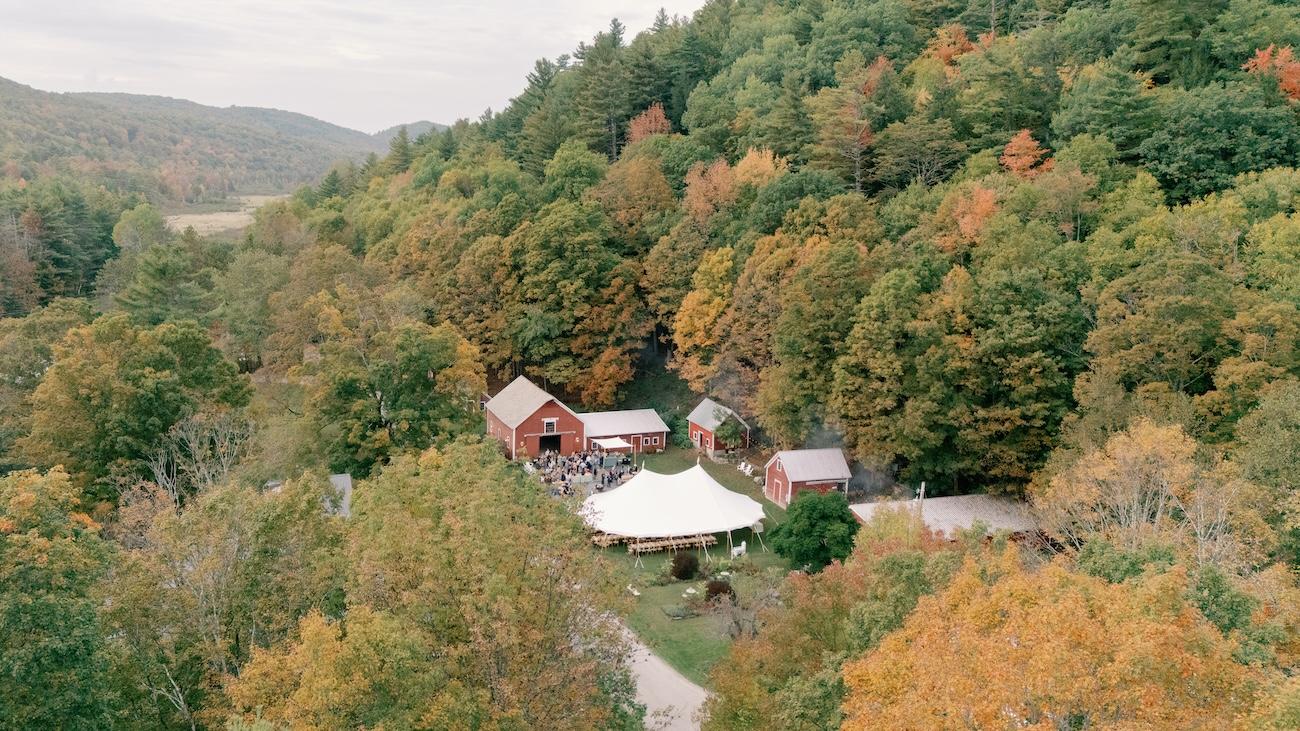 Aerial view of a secluded farm with autumn trees and a large white tent.