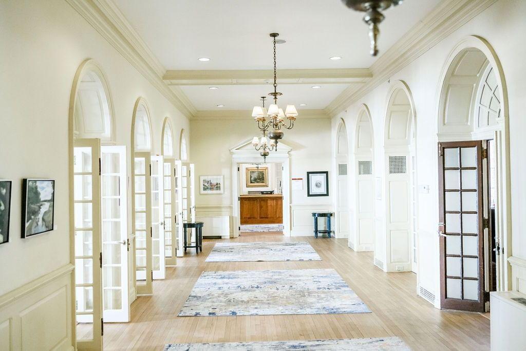 Bright hallway with arched windows and elegant chandeliers.