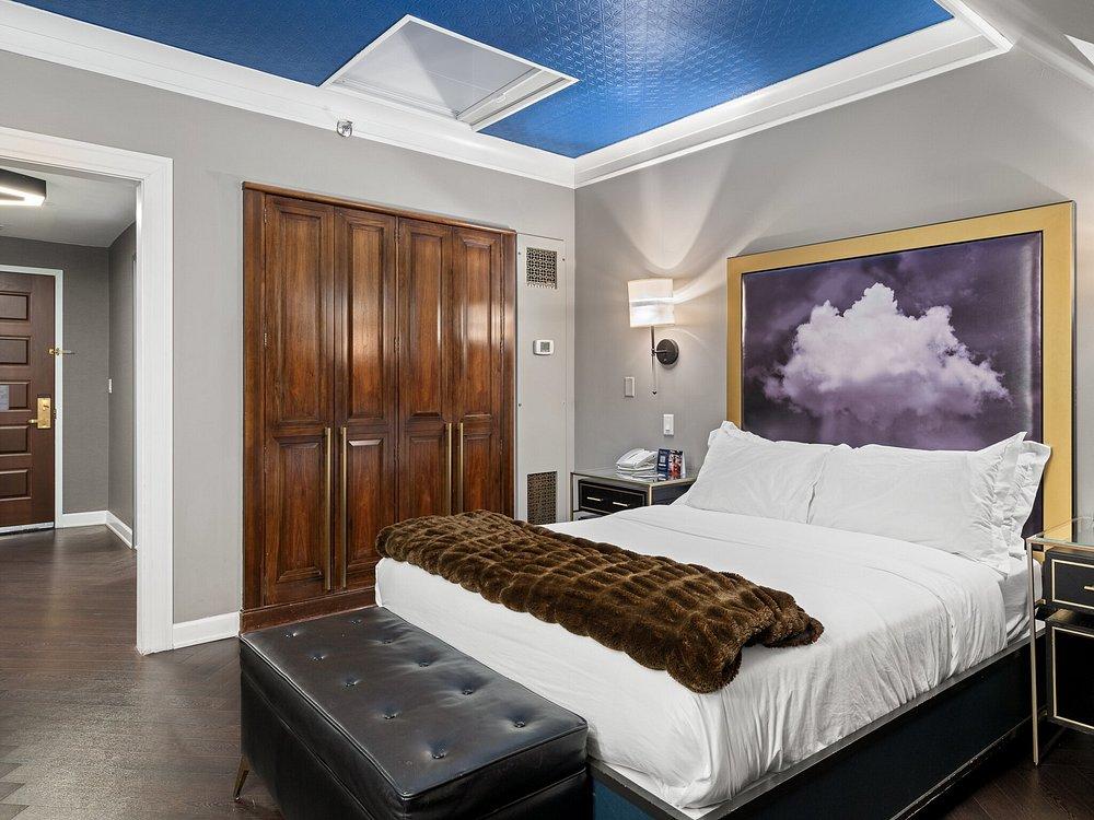 Cozy hotel room with a double bed, wooden wardrobe, and cloud artwork.