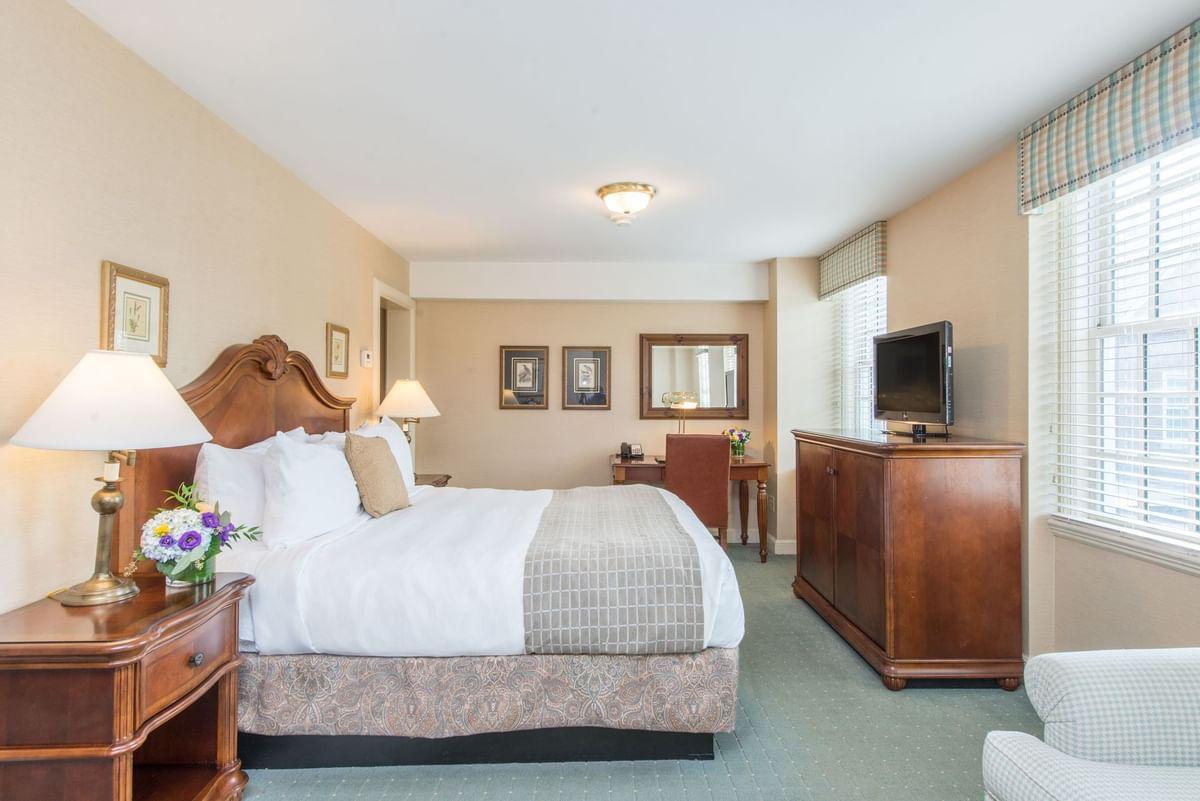 Hotel room with a bed, wooden furniture, and a TV. Bright and clean ambiance.