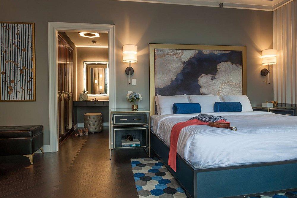Stylish hotel room with a large bed, abstract art, and modern lighting.