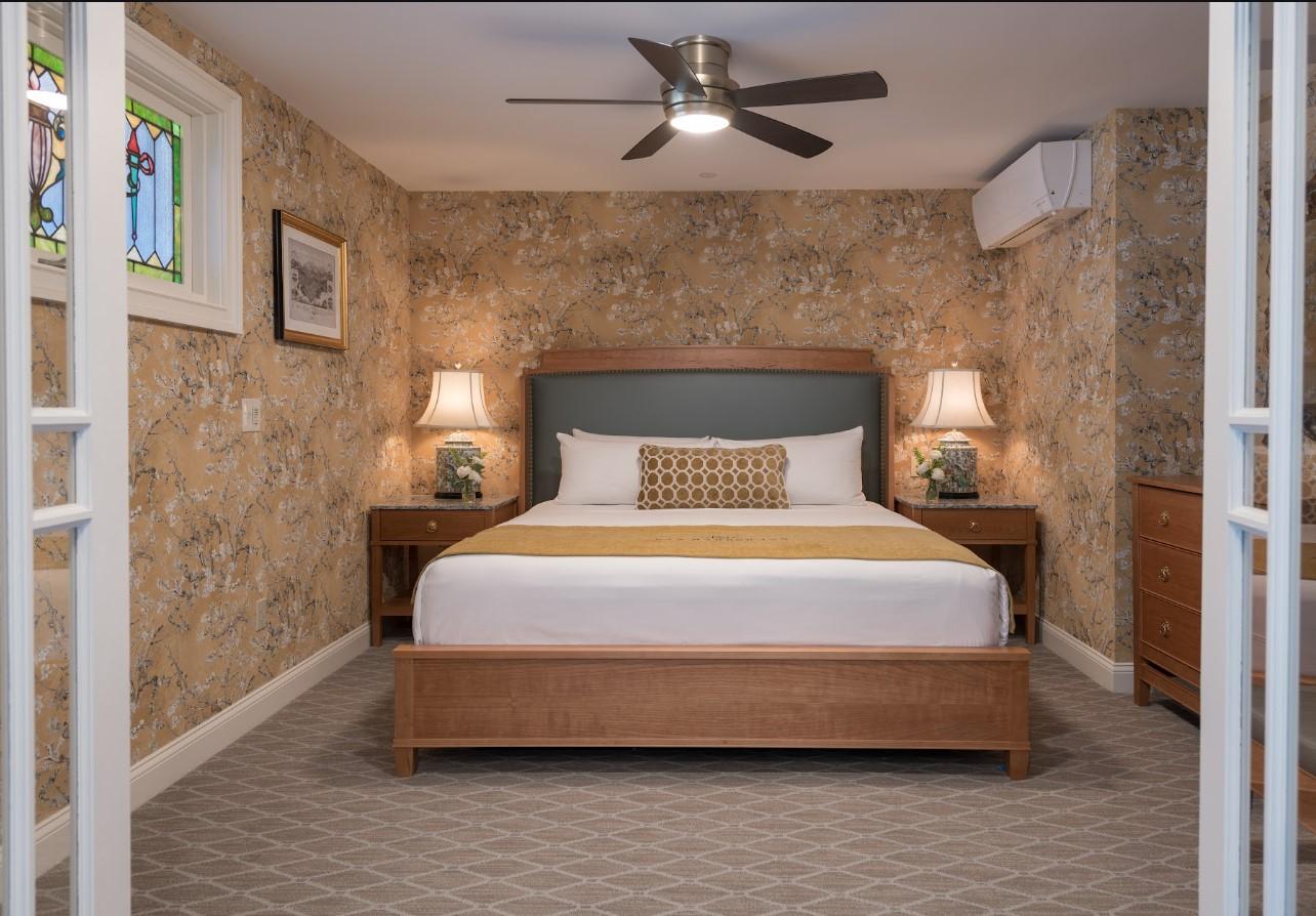 Cozy bedroom with a bed, two lamps, and floral wallpaper.