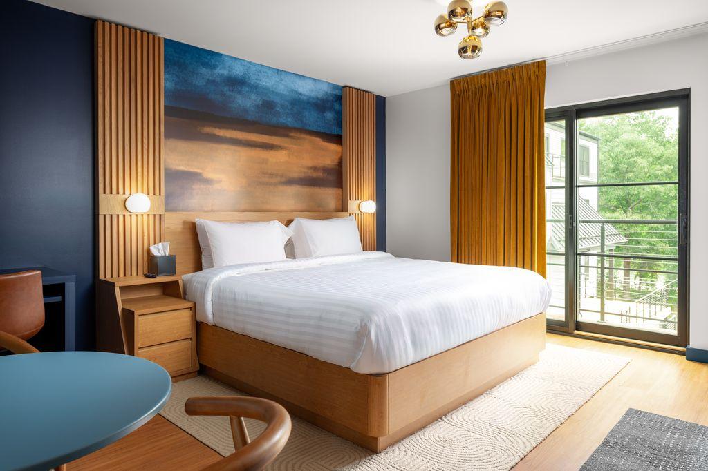 Hotel room with a large bed, wooden accents, and balcony view.