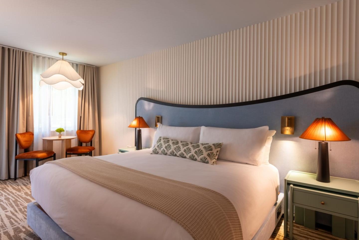 Luxurious hotel room with a large bed, stylish lamps, and warm lighting.