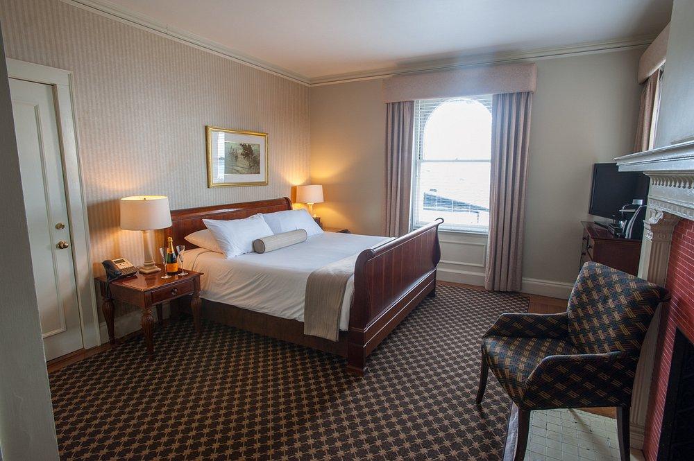 Cozy hotel room with a large bed, armchair, and window with curtains.