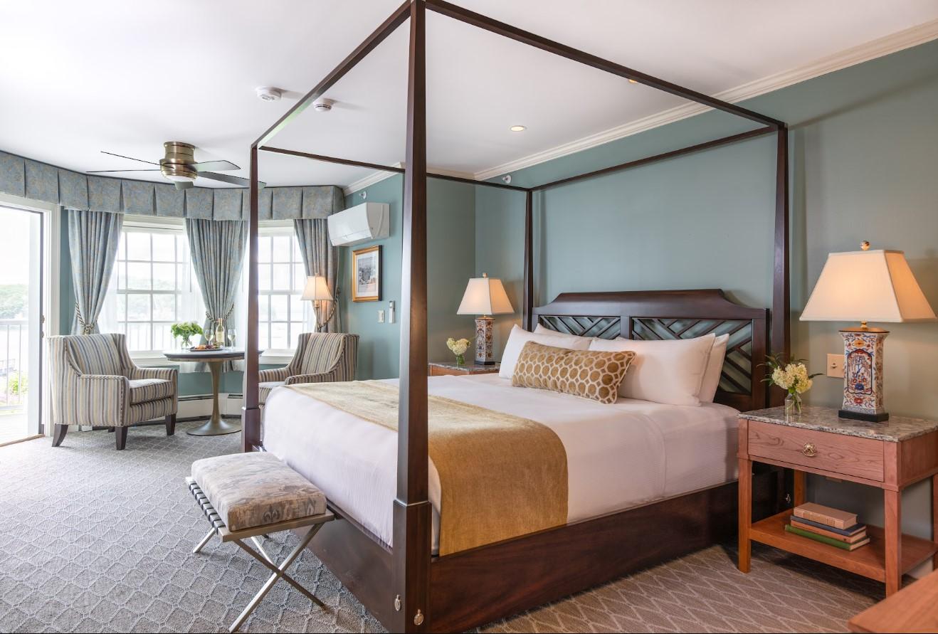 Four-poster bed in a cozy, light-filled room with blue walls.