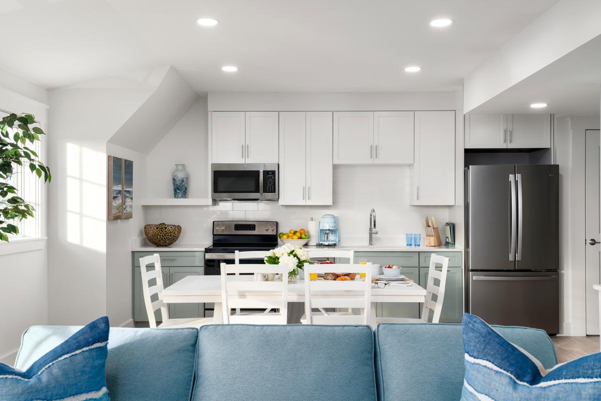 Bright kitchen with white cabinets, blue accents, and a dining table.