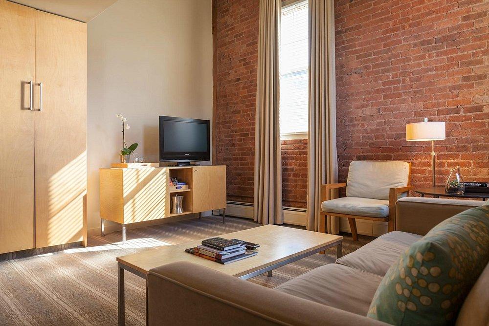 Cozy living room with brick wall, TV, sofa, and armchair.