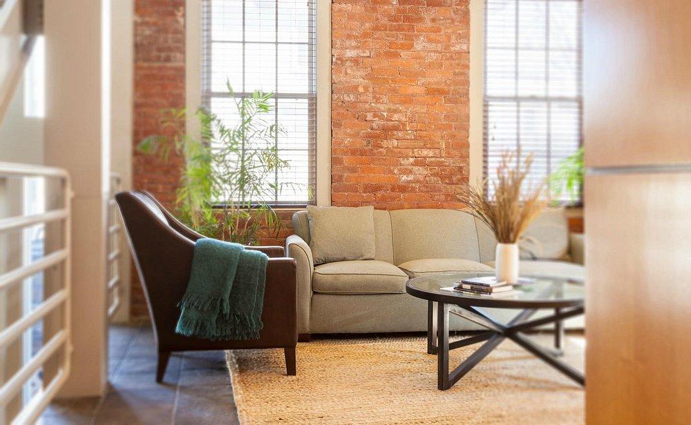 Cozy living room with a sofa, armchair, and brick accent wall.