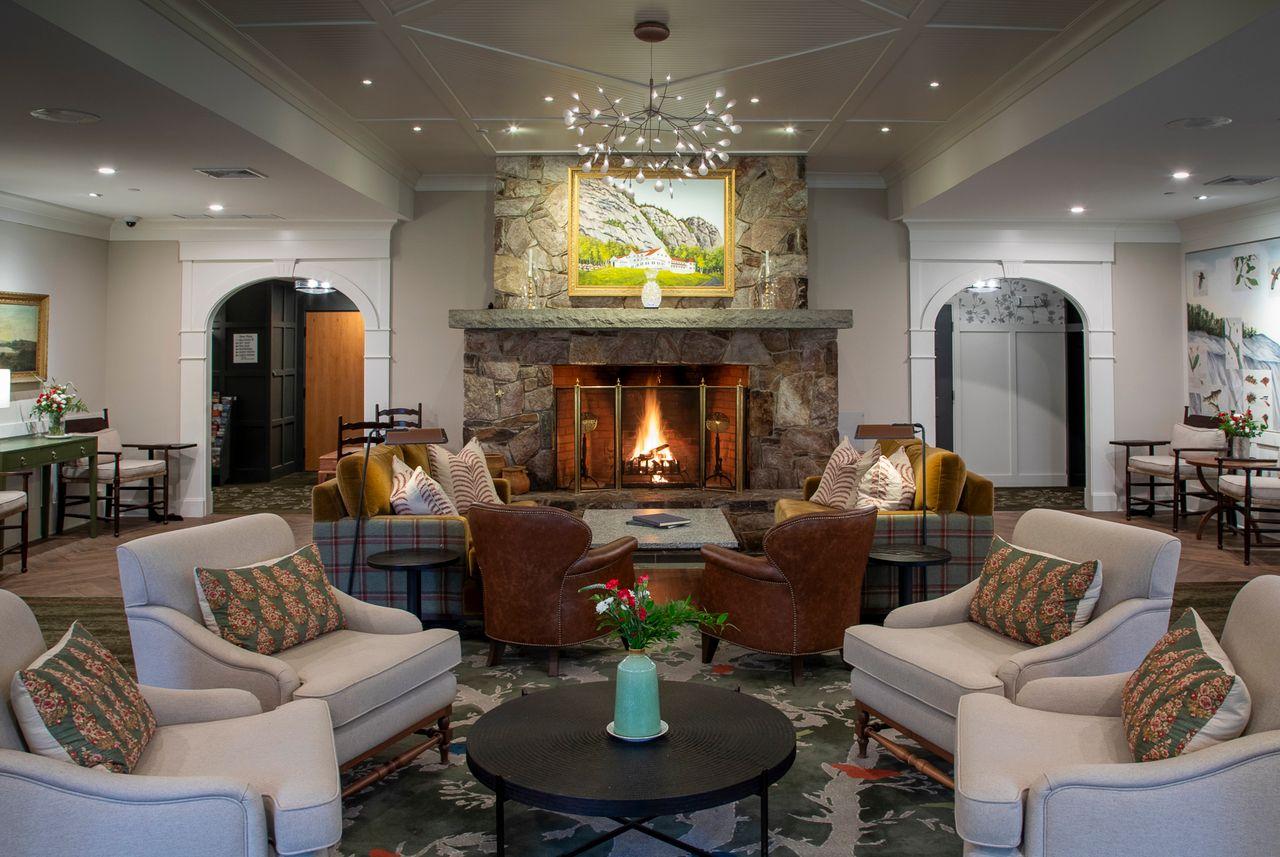 Cozy lounge with armchairs, a fireplace, and a chandelier.