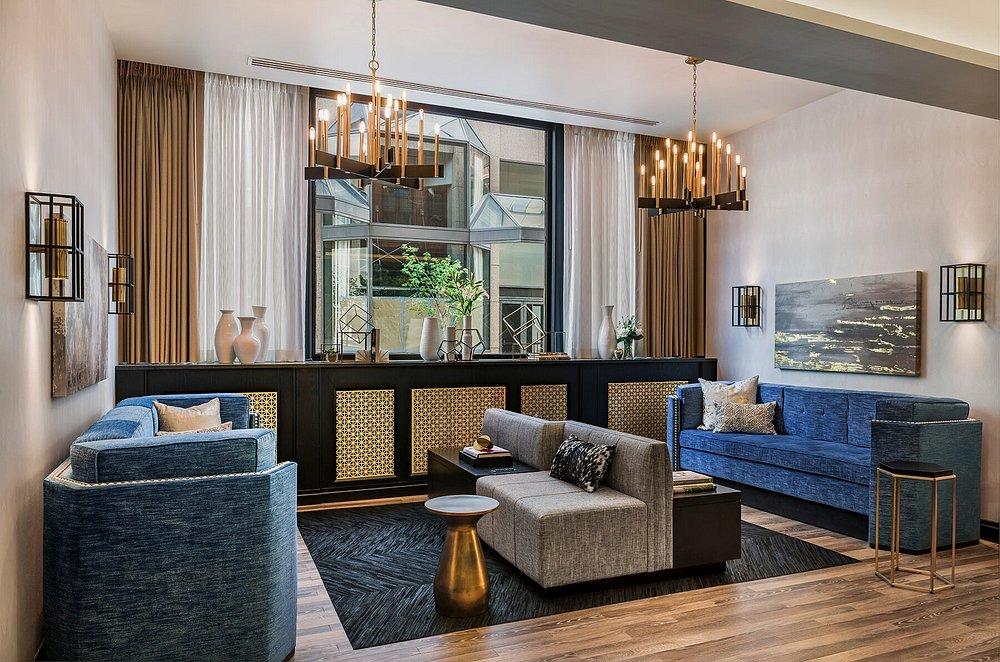 Elegant living room with blue sofas, chandeliers, and large window view.
