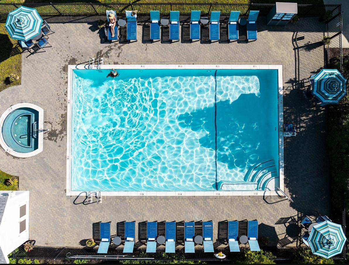Outdoor pool with lounge chairs and umbrellas, seen from above.