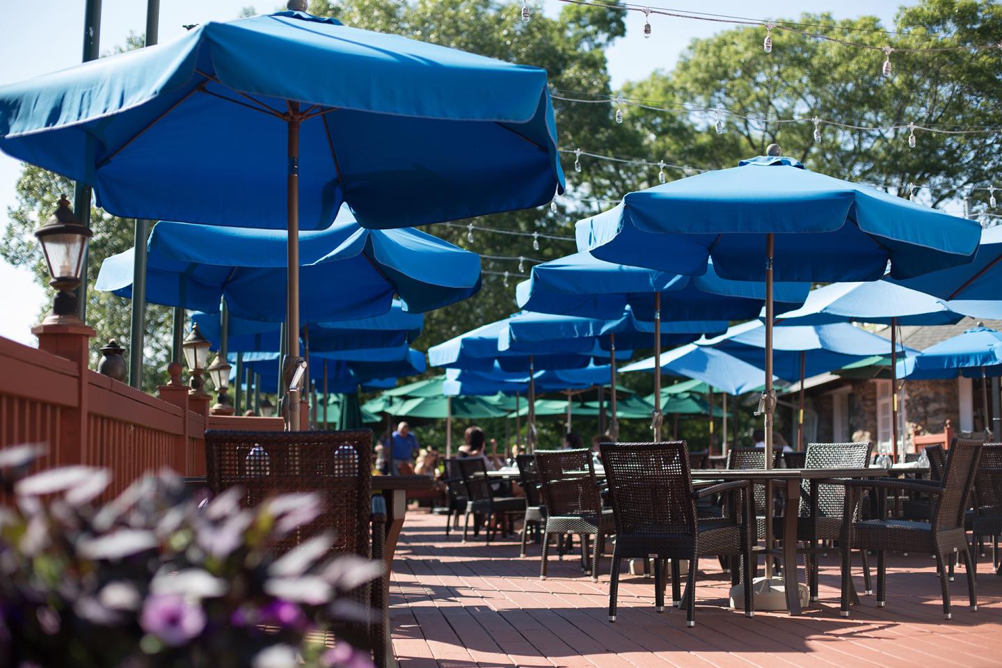 Outdoor patio with blue umbrellas and empty tables.