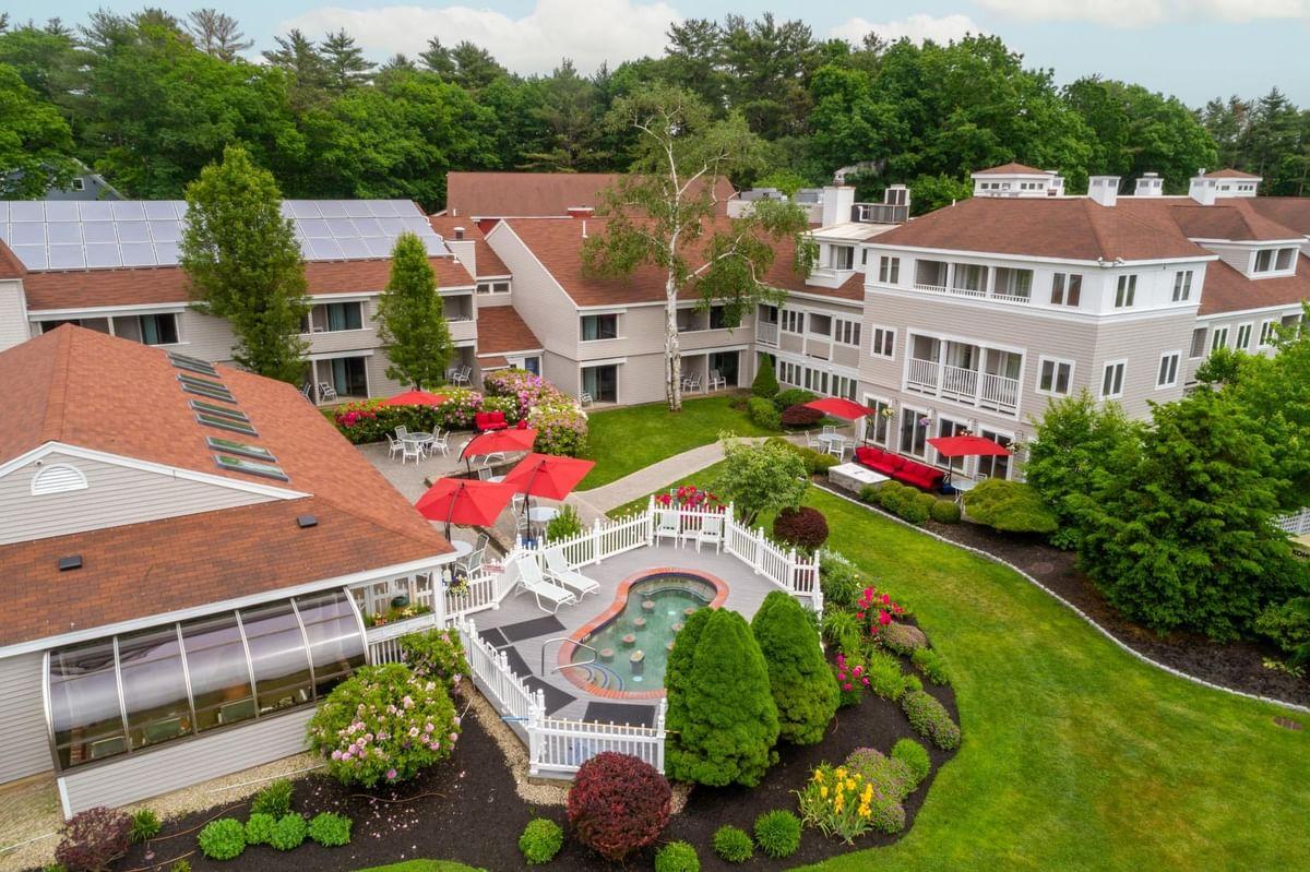 Aerial view of a landscaped resort with red-roofed buildings and a central pool area.