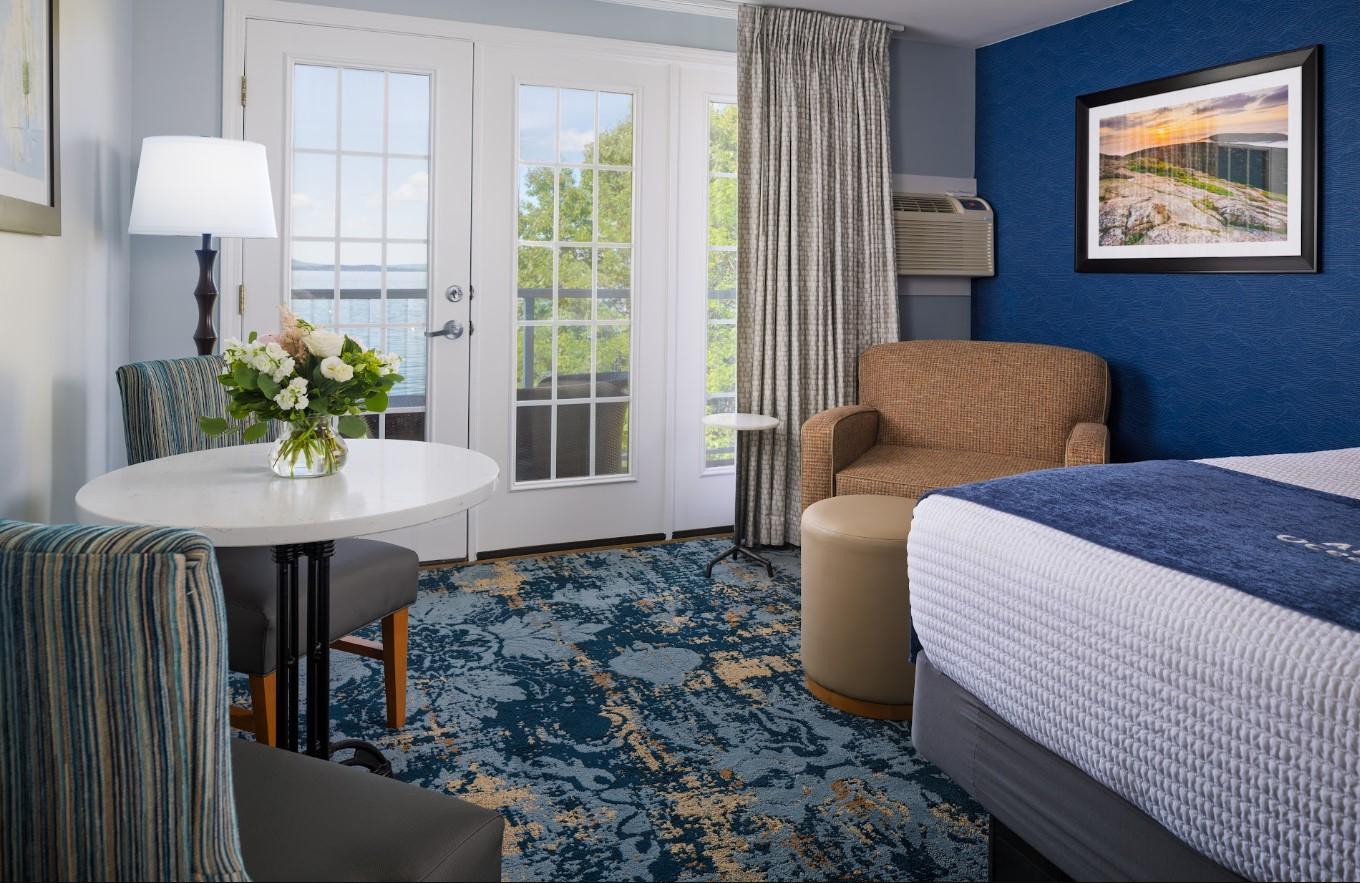 Hotel room with a bed, armchair, round table, and floral carpet.