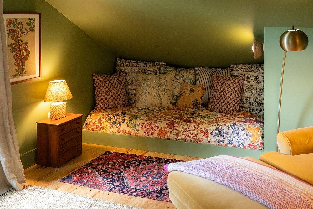Cozy room with a patterned daybed, lamp, and colorful rug.