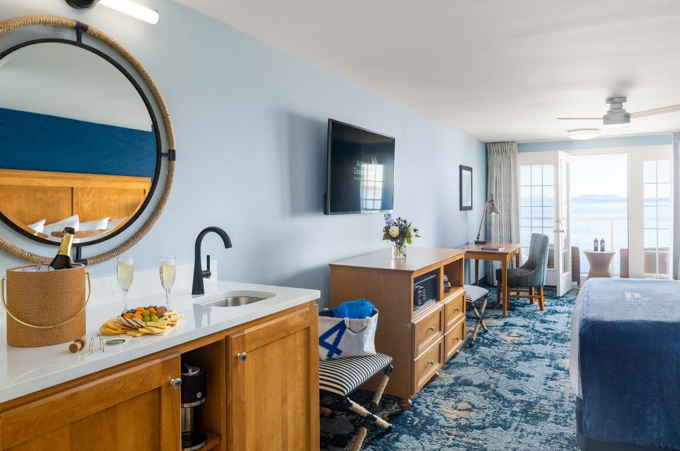 Modern hotel room with blue walls, large TV, and ocean view from window.