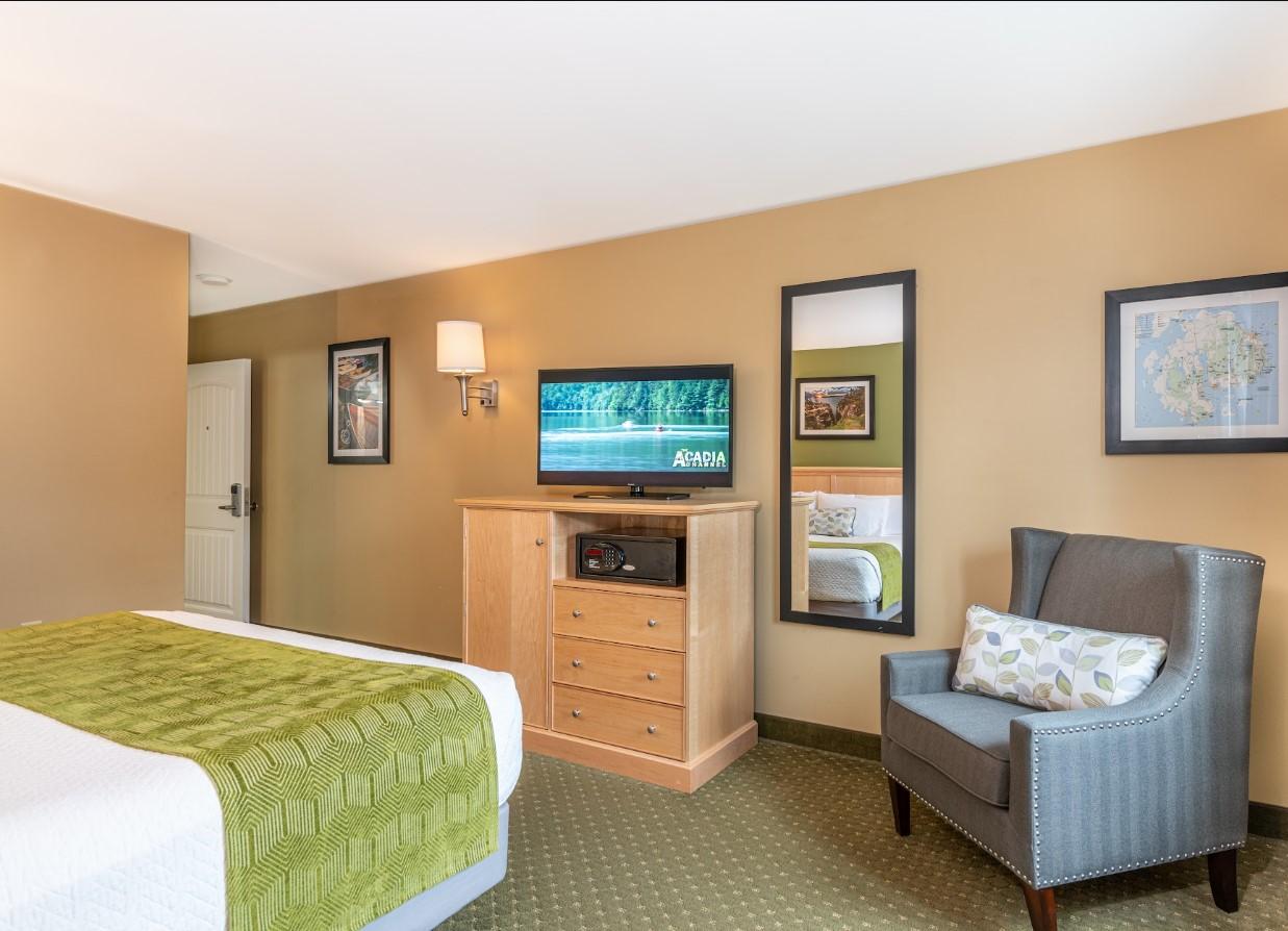 Hotel room with a bed, TV, chair, and green accents.