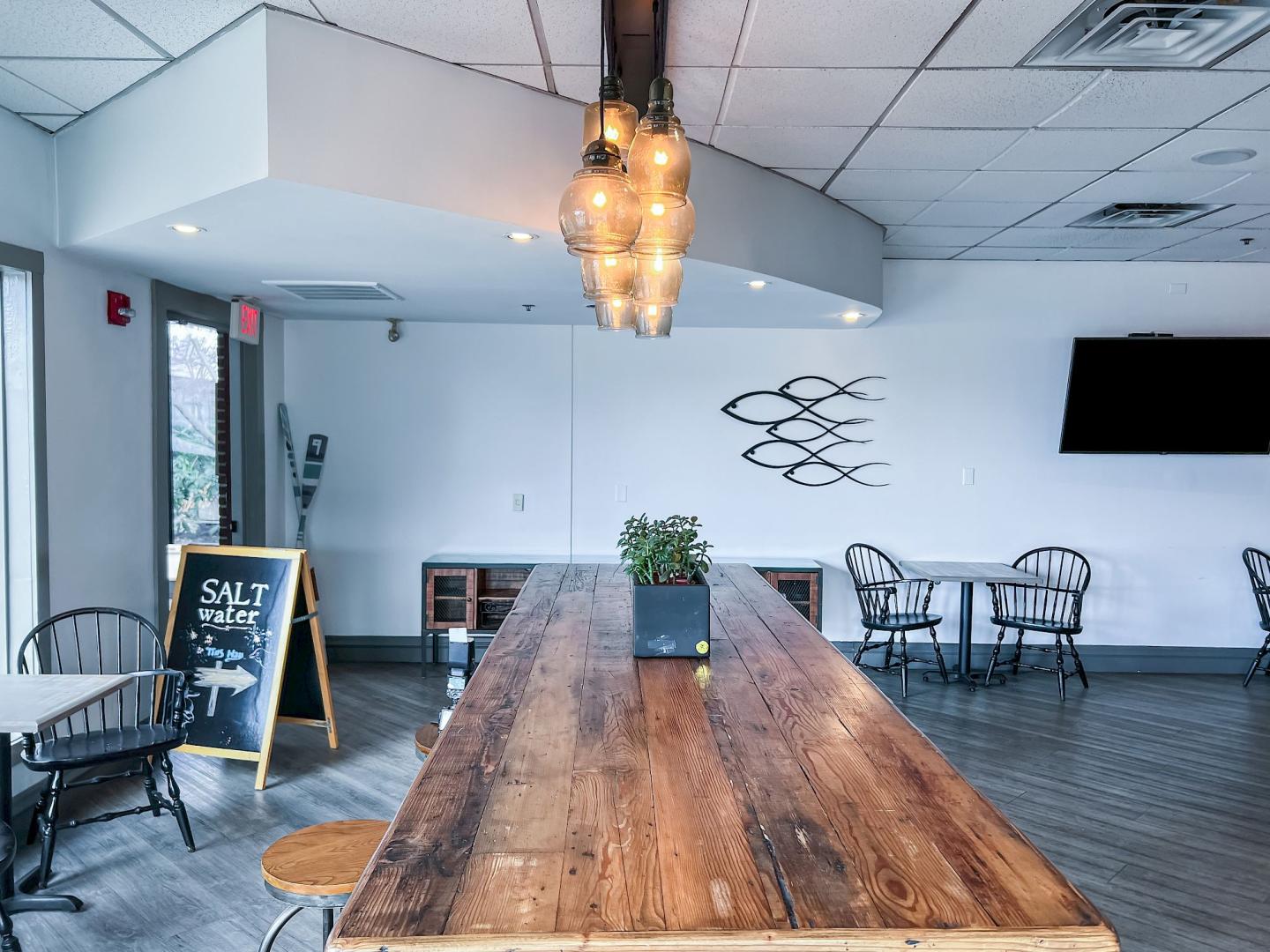 Café interior with wooden table, chairs, and warm hanging lights.