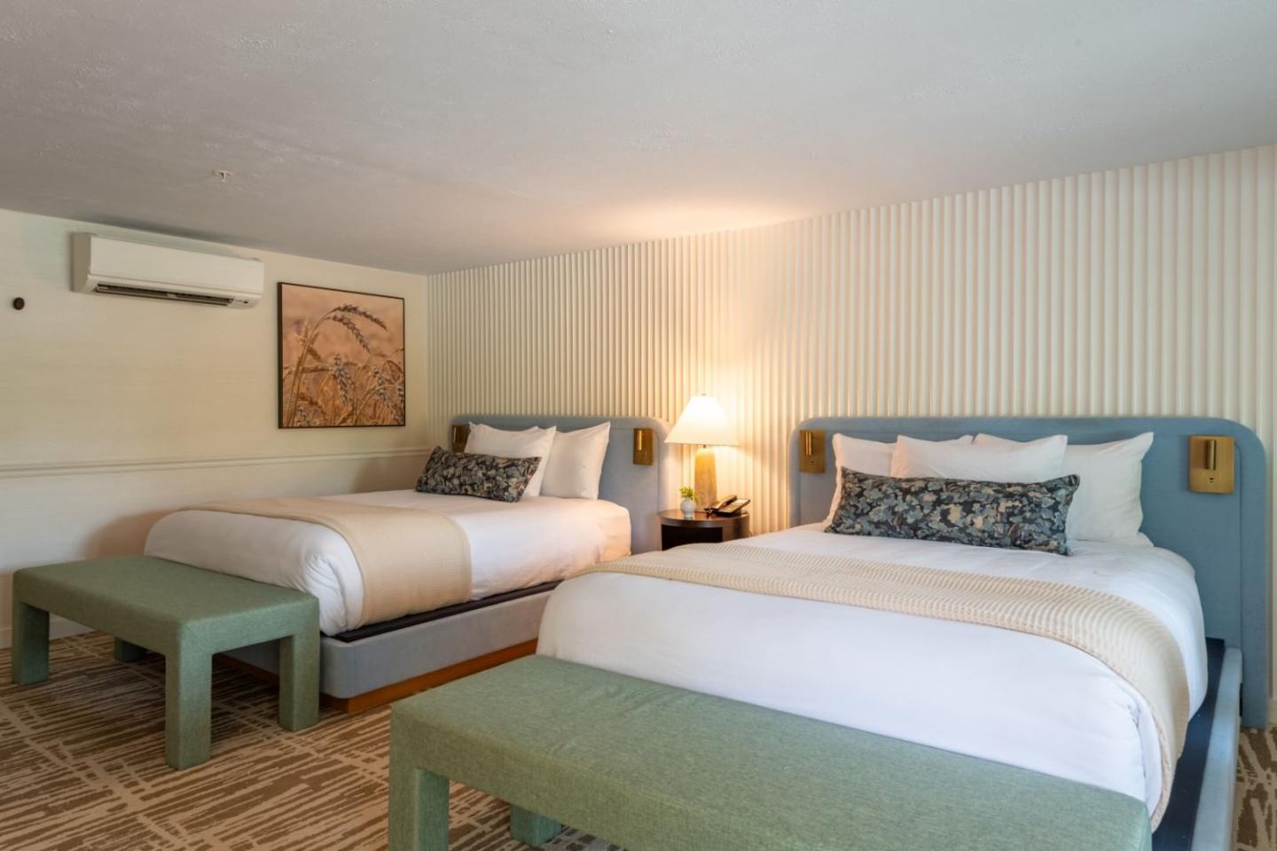 Two neatly made beds in a cozy hotel room with warm lighting.
